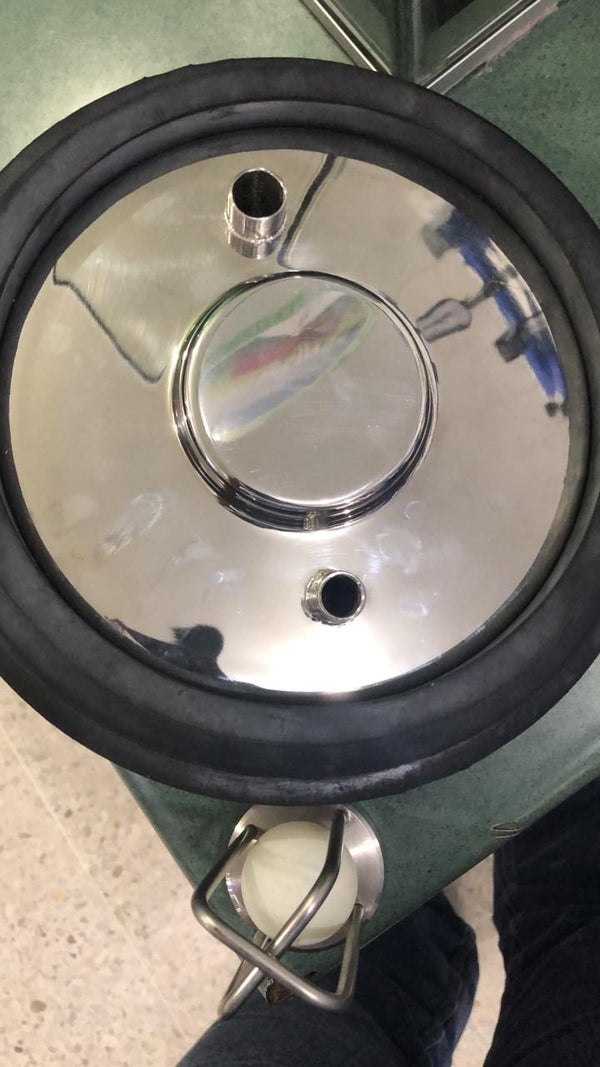 Lado de abajo de una tapa de ordeño en acero inoxidable con la trampa de seguridad de flotador montada en la salida de vacío — foto real
