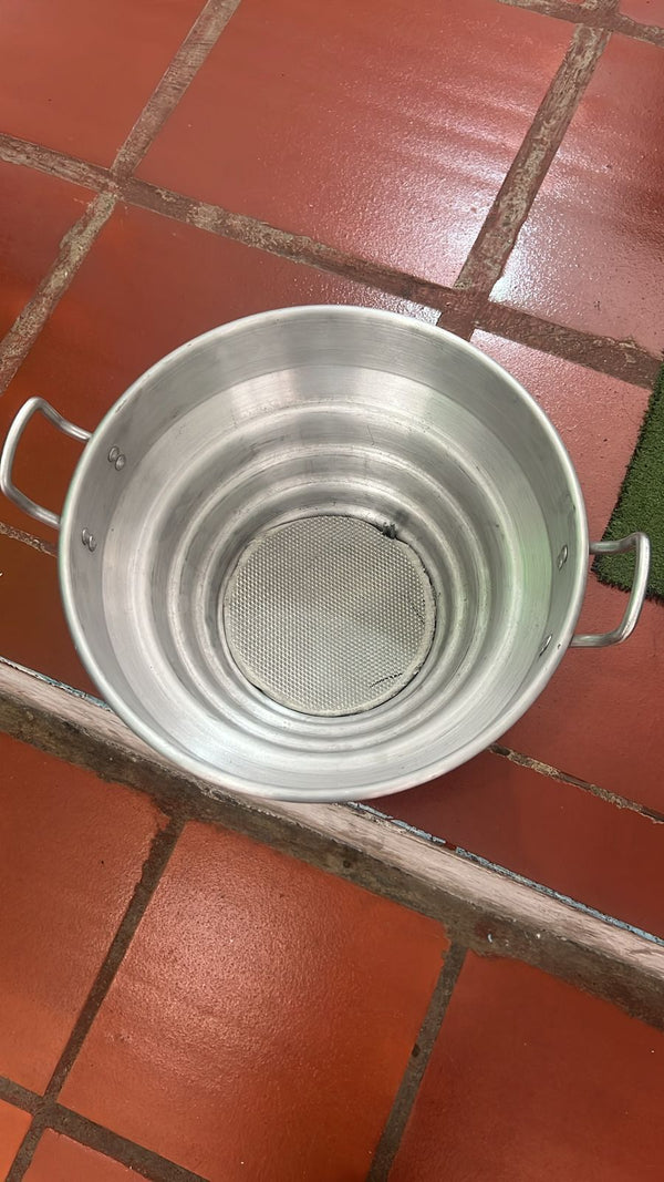 Filtro lechero en aluminio visto desde arriba, con la malla en el fondo — foto real