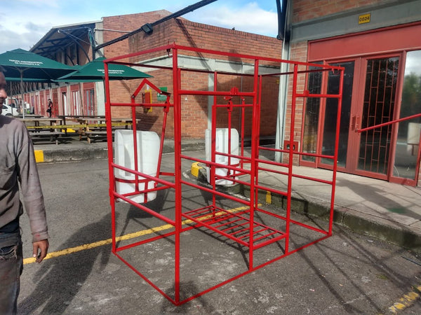 Establo de ordeño fijo en hierro rojo con comederos plásticos, en el patio del taller — foto real